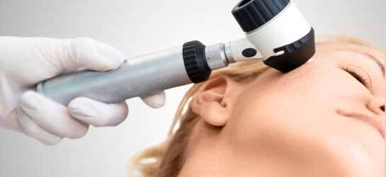 Auf dem Bild ist eine dermatologische Untersuchung zu sehen: Eine Fachärztin oder ein Facharzt betrachtet die Haut im Gesicht einer Patientin mithilfe eines Dermatoskops – einem speziellen Vergrößerungsgerät zur präzisen Beurteilung von Hautveränderungen. Solche Untersuchungen sind essenziell, um eine bakterielle Hauterkrankung frühzeitig zu erkennen und gezielt zu behandeln. Bei Dermacare Wien erfolgt die Diagnose stets unter ärztlicher Aufsicht und mit modernster Technologie, um Entzündungen, Infektionen oder andere Hautprobleme präzise zu bestimmen und individuell zu therapieren.