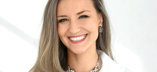 Auf dem Bild ist eine blonde Frau zu sehen, die lächelt und ein weißes Oberteil trägt. Ihr Name ist Minela Biserovic. Sie ist die Geschäftsleitung von Dermacare Wien.