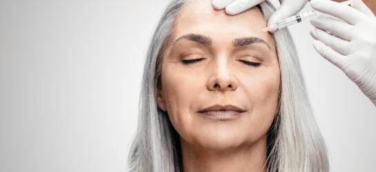 Schluss mit dem Sorgenblick - Soviel kostet Botox gegen Zornesfalte wirklich Auf dem Bild sieht man eine Frau mit grauen Haaren, jedoch sehr glatter Haut, besonders zwischen ihren augenbrauen. Sie bekommt in die Stirn gerade eine Faltenunterspritzung von Dermacare Wien. Dermacare beratet und informiert die Patienten immer sorgfältig vor jeder Behandlung auch über die Botox Kosten Zornesfalte.