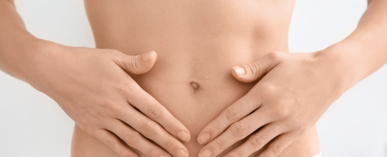 Das zweite Bild zeigt einen flachen, straffen Bauch einer Frau, deren Hände schützend auf dem Unterbauch liegen. Dieses Bild kann symbolisch für die Phase vor dem Auftreten von Dehnungsstreifen stehen – also noch ohne sichtbare Veränderungen. Es eignet sich hervorragend zur Veranschaulichung der Frage „Wie fangen Schwangerschaftsstreifen an?“, denn genau in diesem Zustand beginnt die Haut auf Dehnung zu reagieren. Der Bauch ist bei Schwangerschaftsstreifen eine besonders anfällige Region, da er im Laufe der Monate stark wächst.