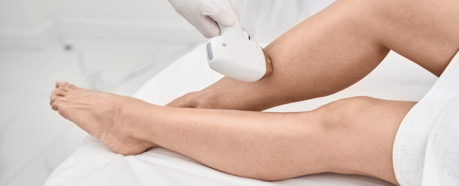 Nahaufnahme einer professionellen Laser-Haarentfernung an den Beinen in einer modernen Praxis. Die Behandlung wird präzise und schonend durchgeführt, um eine effektive dauerhafte Haarentfernung zu erzielen.