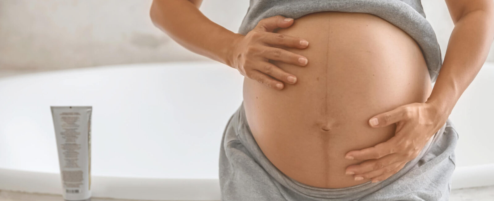 Das dritte Bild zeigt den Bauch einer schwangeren Frau, die ihre Haut mit beiden Händen eincremt. Ihre Haut ist bereits stark gespannt, und eine sichtbare Linea nigra (Schwangerschaftslinie) zieht sich über den Bauch. Dieses Motiv zeigt sehr anschaulich, wie wichtig Pflege ist, um Schwangerschaftsstreifen am Bauch vorzubeugen. Genau in dieser Phase fragen sich viele Frauen: „Wie fangen Schwangerschaftsstreifen an?“ – und beginnen, gezielt Feuchtigkeitspflege einzusetzen, um ihre Haut elastisch zu halten.