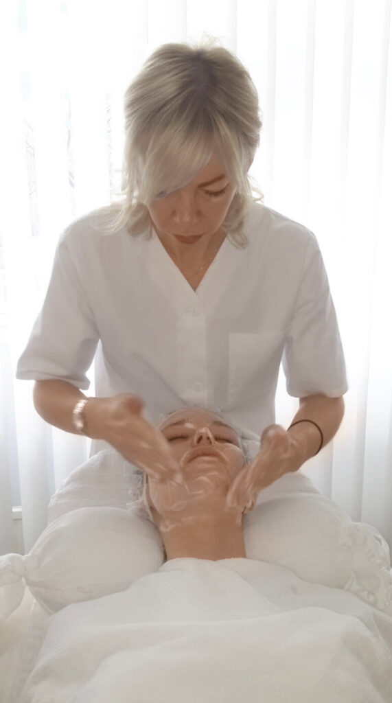 Hier sieht man eine entspannende Behandlung bei Dermacare Wien gegen unreine Haut durch Stress. Eine Frau wird gerade eingecremt und liegt ruhig da.