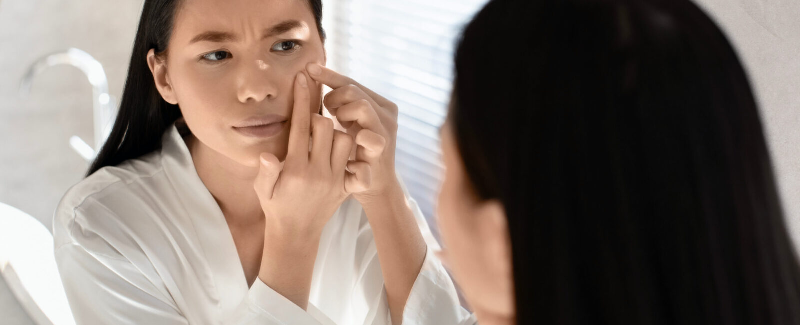 In diesem Bild sieht man wie eine Frau Pickel ausdrückt. Sie versucht ihre Pickel vor dem Date loszuwerden.