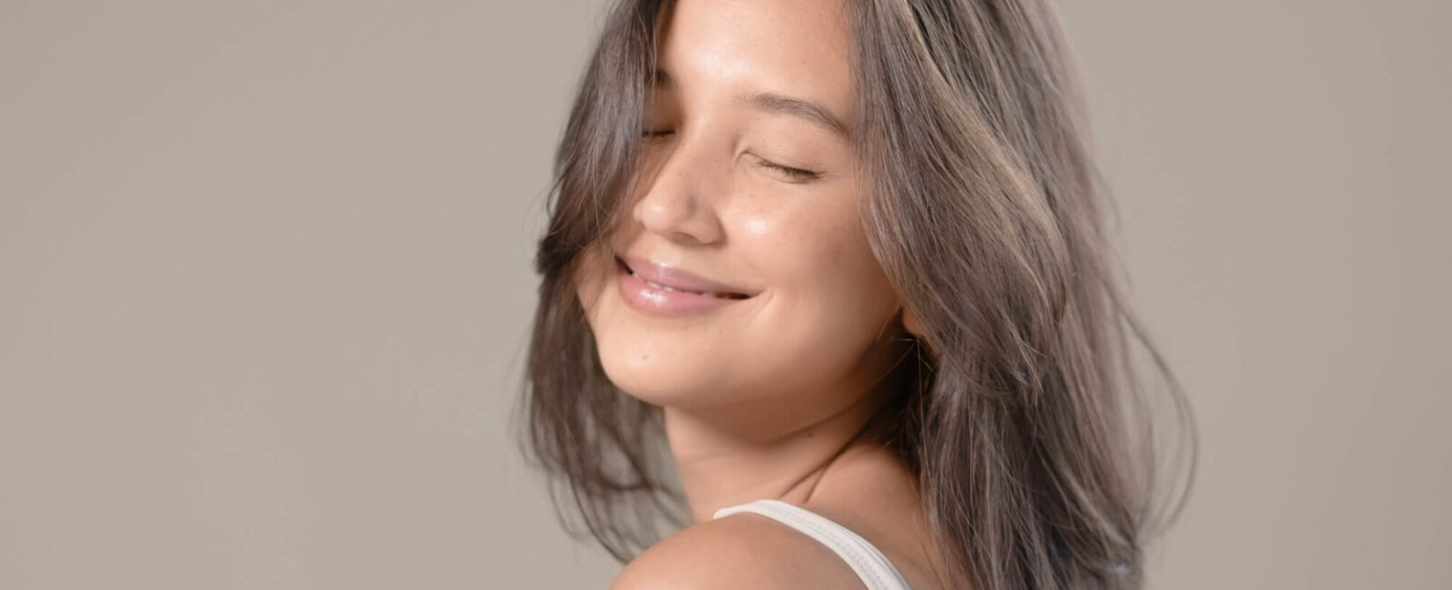 Ungeschminkt natürlich schön – wir verraten wie Ungeschminkt natürlich schön - genau dafür steht dieses Bild. Eine braunhaarige Frau lächelt mit geschlossenen Augen.