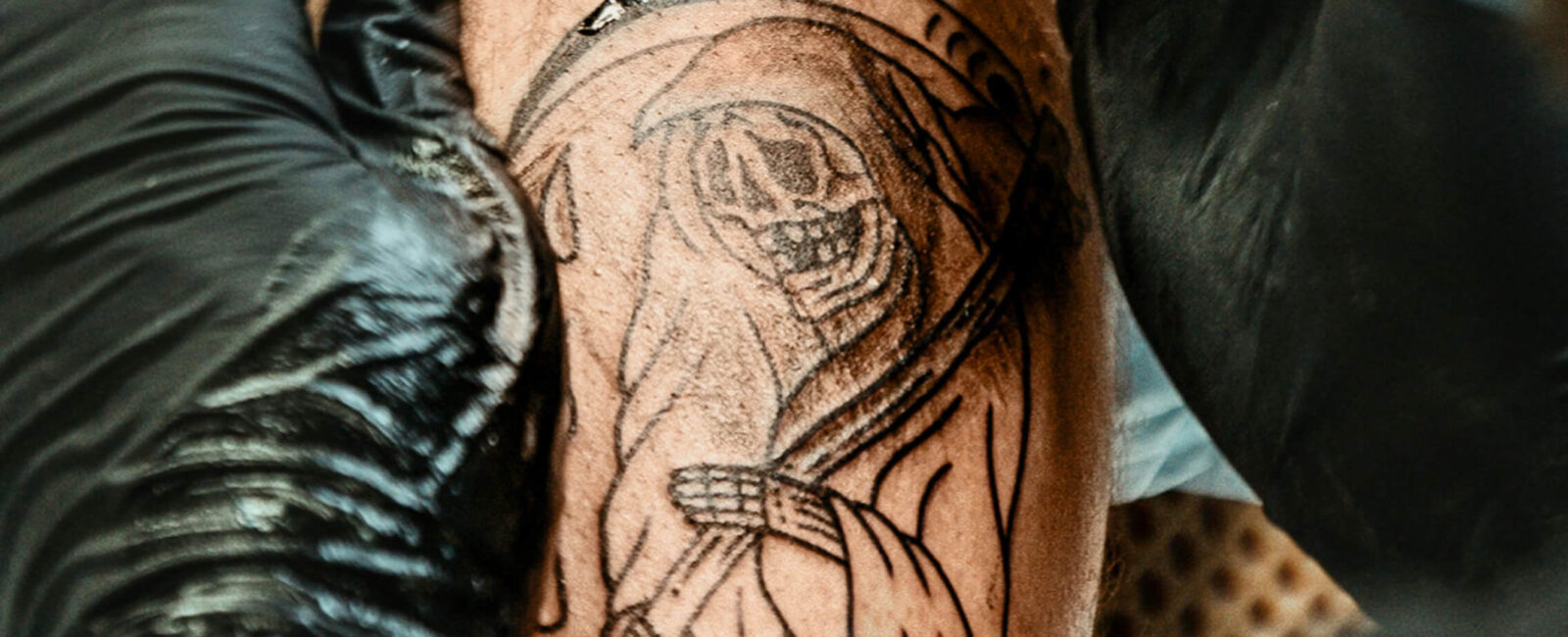 Hier auf diesem Bild sieht man eine Person die sein Tattoo loswerden möchte. Man sieht sein schlecht gestochen Tattoo auf der Schulter das den Sensenmann zeigt.